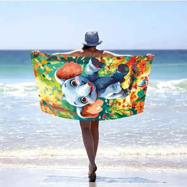 Kolorowy ręcznik plażowy z mikrofibry 100x180 cm z nadrukiem bajkowego niebieskiego słonika w barwnym lesie.