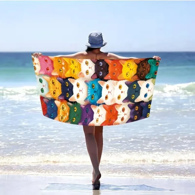 Ręcznik plażowy z mikrofibry 100x180 cm z gęstym wzorem kolorowych, bajkowych kocich pyszczków.